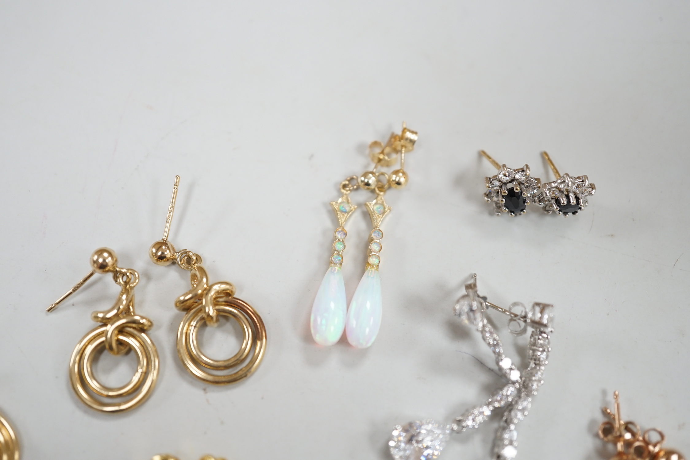 Ten assorted pairs of 9ct and 9ct and gem set earrings, including white opal, gross weight 22.3 grams, together with three other pairs of yellow metal and gem set small ear studs(lacking butterflies)